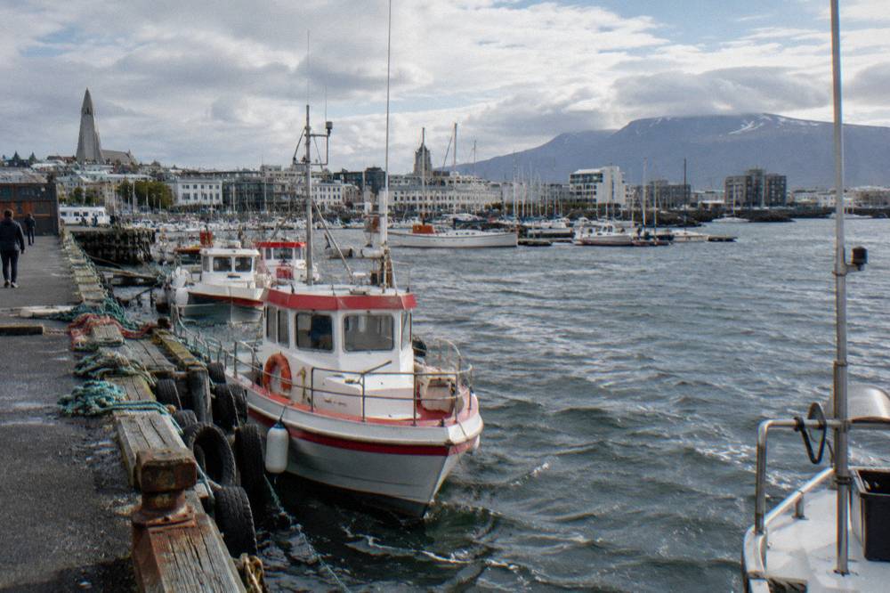 Old harbour in Reykjavik with small boats moored and distant mountains