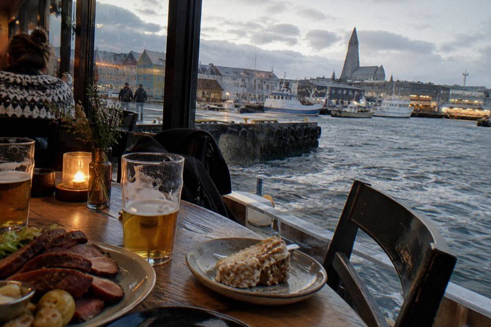 A table of shared Icelandic dishes and glasses of beer in a warm Reykjavik restaurant