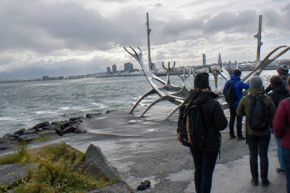 Guides and visitors gathered at a Reykjavik harbour landmark before a walking tour