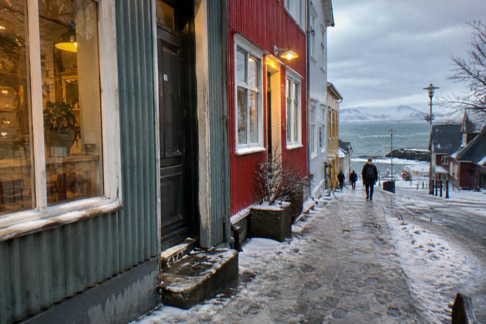 Snow dusted street in Reykjavik city centre with warm shop lights in late afternoon