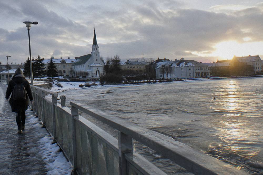 Low golden winter sun over snowy Reykjavik rooftops and a quiet city street